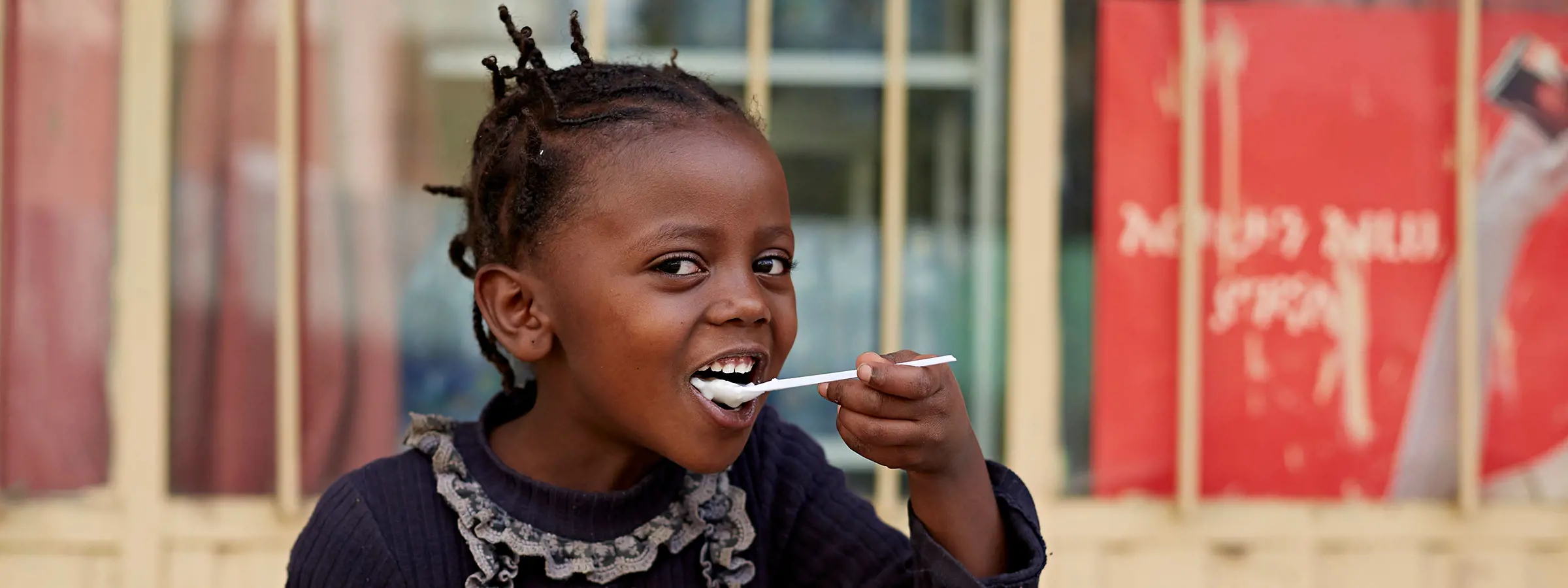 Niña de Etiopía comiendo yogur