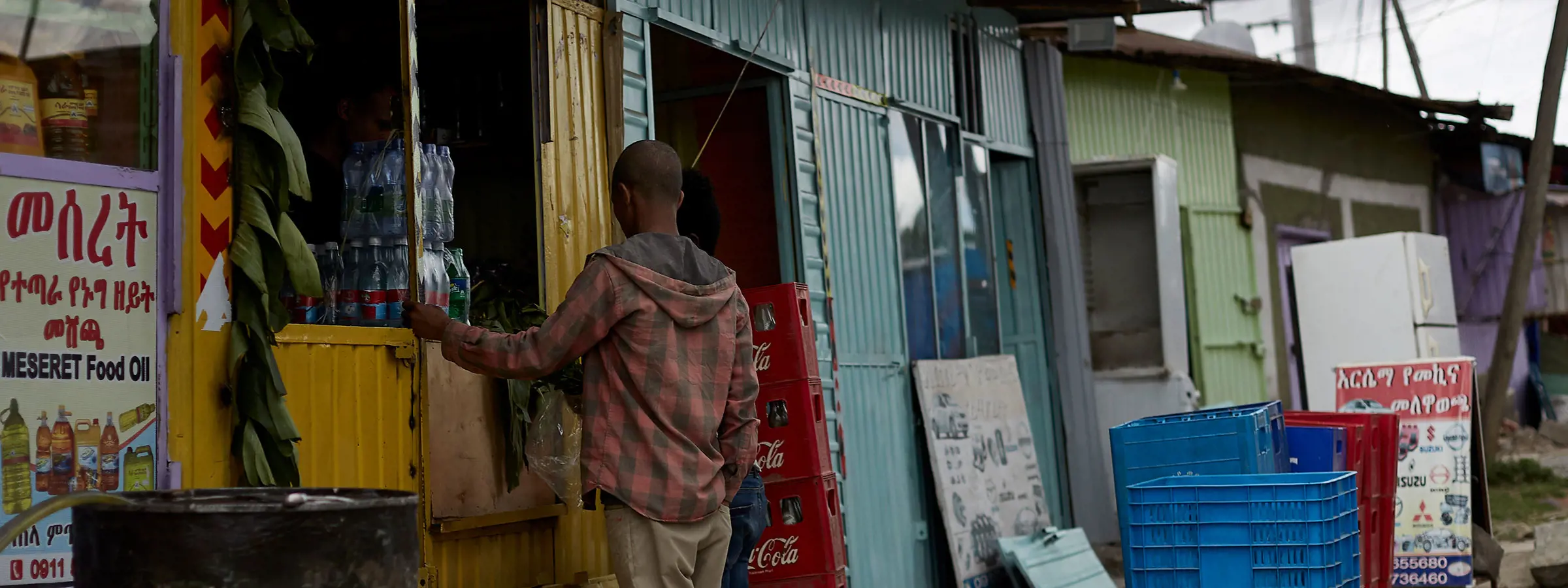 joven en Etiopía frente a kiosco con bebidas cola
