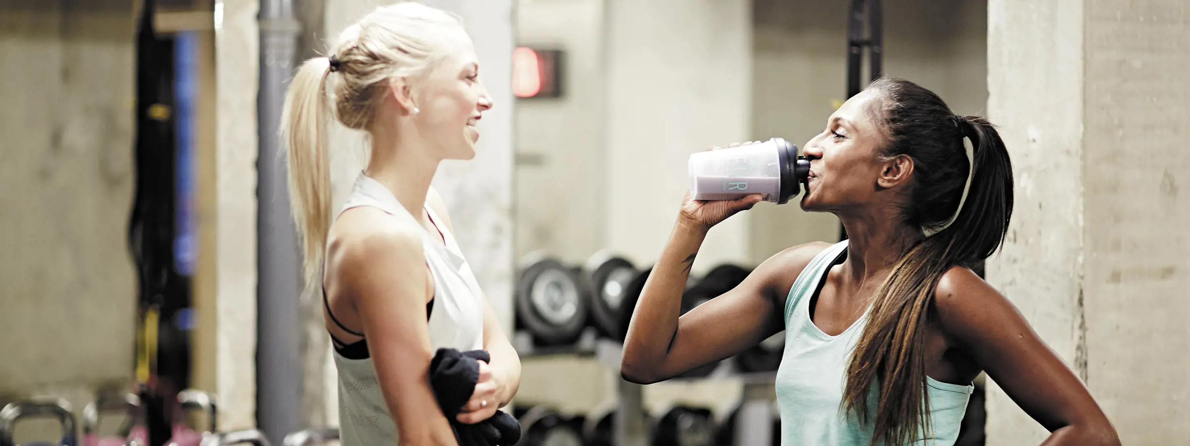 mujeres bebiendo shakes de proteínas mientras pausan su entrenamiento